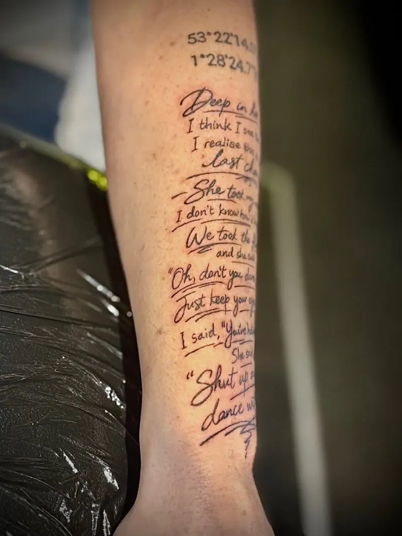 Comprehensive script tattoo with song lyrics and coordinates