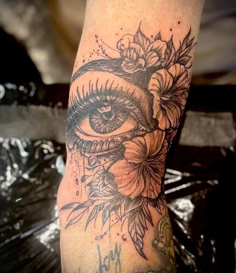 Realistic eye and floral illustrative arm tattoo